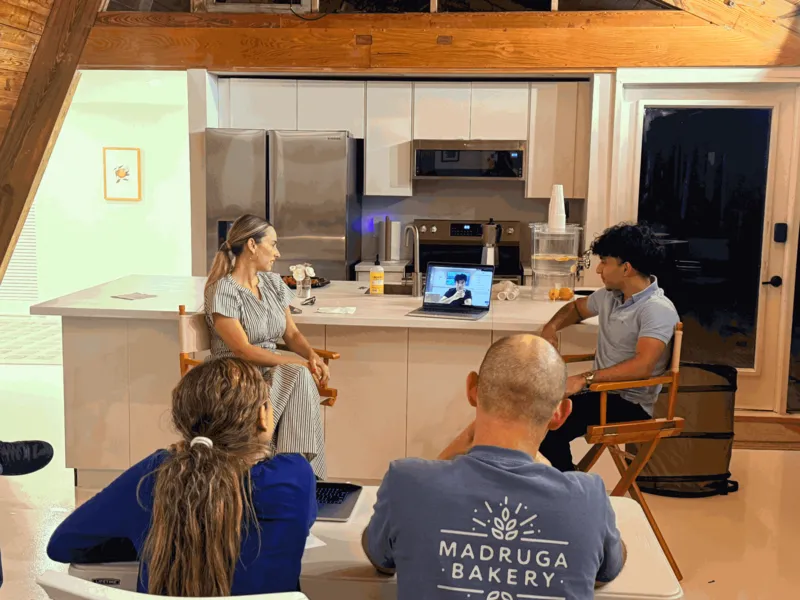Malik and a woman in director’s chairs watch Glutt’s launch video on a laptop while an audience looks on